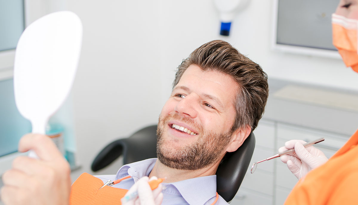 Ein Mann freut sich über seine schönen Zähne durch die ästhetische Zahnheilkunde in Herzogenrath.