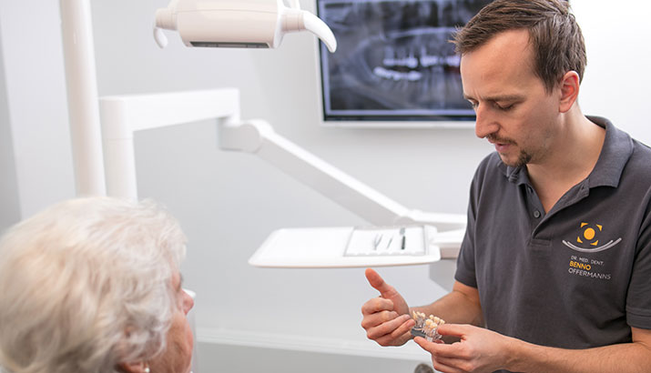 Dr. Benno Offermanns erklärt einer gehörlosen Patienten mit den Händen die Behandlung mit Zahnersatz.