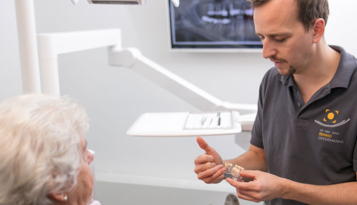 Dr. Benno Offermanns erklärt einer gehörlosen Patienten etwas in der Zahnarztpraxis. 